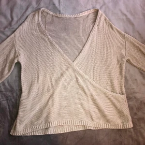 Lindex beige stickad wrapover tröja. - Säljer en söt beige stickade wrapover v-neck tröja från lindex. Den sitter väldigt fint och är i en jättebra skick! 