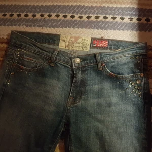 KONTAKTA INNAN KÖP NU Vintage bootcut jeans - Är annonsen kvar är plagget kvar😊 Vintage lågmidjade bootcut jeans, köpta här på plick i april 2021. Säljer då de blivit för små i låren för mig.  Super fina med ljusgröna diamanter/rhinestones. I väldigt bra skick, har ett litet hål vid hälen som man ser på sista bilden, det var där när jag köpte de, men man tänker inte på det. Midjemått rakt över:41 cm. Innerbenslängd: 83 cm. Frakt ingår inte!