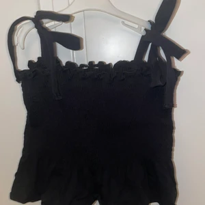 Svart linne - Säljer ett svart linne från SHEIN med knytningar på armarna. Passar perfekt till allt. Kontakta mig vid intresse 