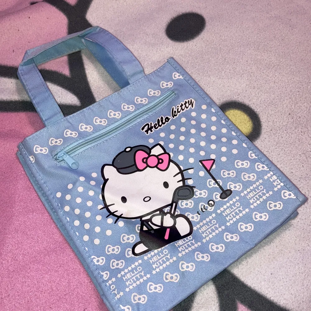 En väska perfekt för din matlåda❗️ Hello Kitty spelar golf på en ljusblå bakgrund. Väska är helt ny men har fått lite små fläckar från skåpet där den leagat.. Väskor.