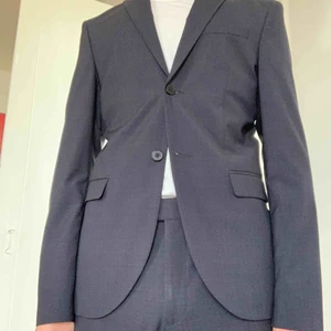  - Hm-kostym i 100% ull. Blå med ett diskret mönster  Byxorna något kortade. Kavajen är inte använd och armarna är oförändrade i längden.  slim fit. Två knappar. Enkel sprund.