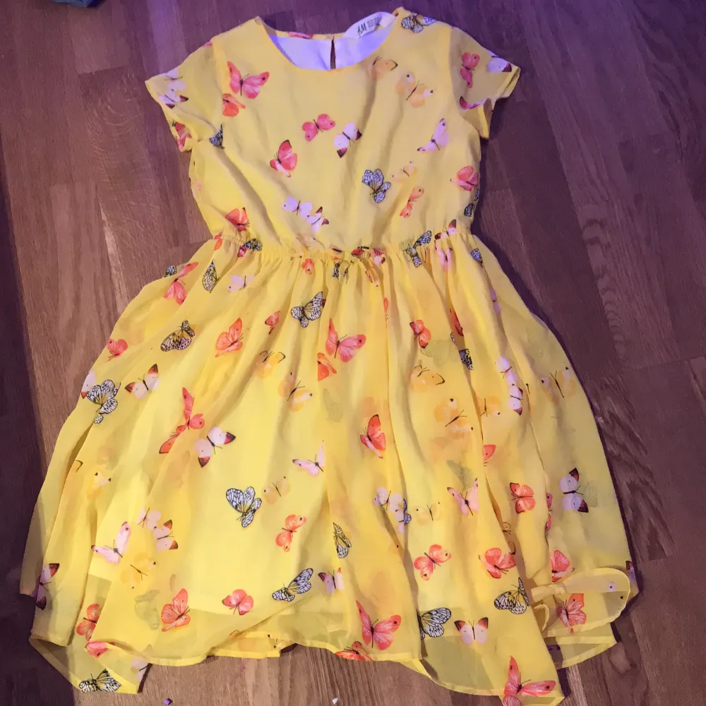En gul kortärmad klänning med fina färglagda fjärilar!. Klänningar.