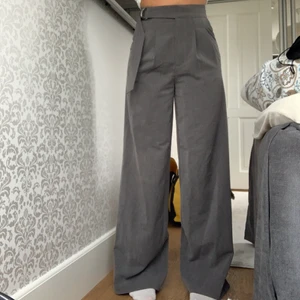 Gråa kostymbyxor  - Säljer dessa kostymbyxor från Na-kd i storlek 34. Du knäpper dom i mitten av byxan och sedan går det ett skärp över knäppena. Knappt använda🤍