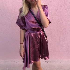Kimono klänning - Säljer min superfina rosa/lila kimono klänning ifrån na-kd i storlek 34. Klänningen är endast provad och lappen finns kvar. Den har ett litet hål precis i sömnen under där knappen sätts i (se sista bilden) men det syns inte när klänningen knyts.🥰❤️😊