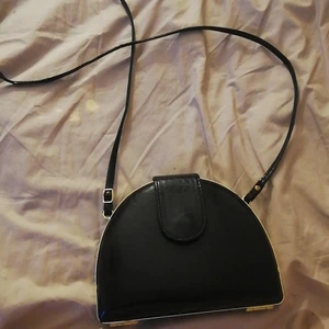 Handväska  - Svart handvöska med guld runt öppningen. Materialet är hårt. Kommer inte ihåg vart jag fick den ifrån men jag har aldrig använt den. 