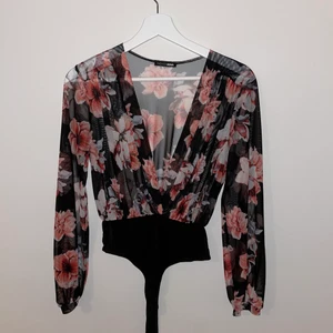 Blus - En blommig blus/body i genomskinligt material jättefin och luftig, använd fåtal gånger. frakt ingår i priset