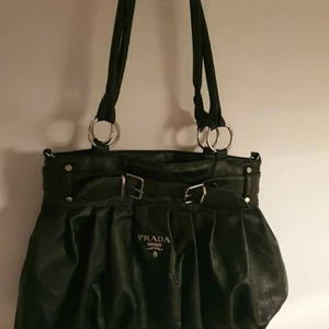 Pradaväska - En superfin Pradaväska( inte äkta) i mjukt lädermaterial med axelband som inte skaver! I väskan finns massor med fickor, plats och den är i mycket gott skick. Jag säljer den för att den inte är min stil längre och hoppas någon annan vill köpa den 🌷❤