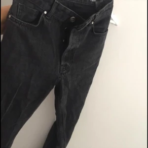 Svarta jeans från Never denim strl XS - Svarta jeans med knappar, slutar vid ankeln på mig som är 171 cm. Använda men i fint skick