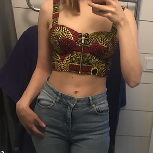 Mönstrad bustier/topp med dragkedja, stl. XS - Svinsnygg, färgglad bustier med dragkedja. Bra stöd vid bysten, fin passform, väldigt fint skick. Leveransavgift tillkommer när paketet har vägts (om köparen vill att plagget ska postas) och jag vet vad summan blir.