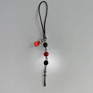 En phonecharm med röda och svarta pärlor, en drop charm & ett svärd 🗡 🩸15kr frakt✨ Fram till 20e september går 40% av vinsten till Cancerfonden🎗för min kusin Emils skull❤️