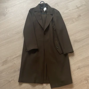 Mossgrön/brun höstkappa - Aldrig använd. Svårt att se färgen den är mörkt mossgrön och i vissa ljus så ser den brun ut