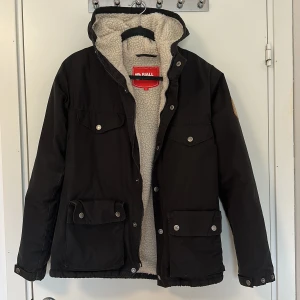 Fjällräven jacka - Säljer min gamla fjällräven jacka med ull i. Många fickor och går att spänna till längst ner i jackan (se bild 3). Stoelek xs men passar både S & M då den är stor i storlek.