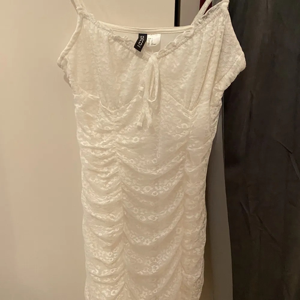 Kort vitt klänning som formar kroppen fint. Det är fina vita detaljer på.  Pris är diskuterbart😊. Klänningar.