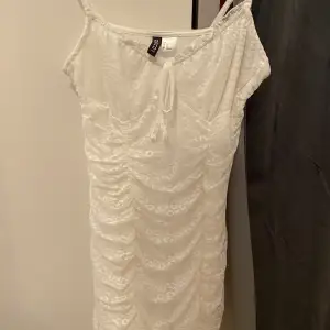 Kort vitt klänning som formar kroppen fint. Det är fina vita detaljer på.  Pris är diskuterbart😊