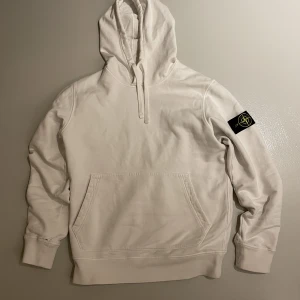 Stone Island Hoodie storlek:M - Säljer min vita Stone island hoodie i storlek: M, lite sliten vid slutet av armarna men syns inte när man har den på