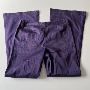 Lila byxor - Lågmidjade lila bootcut/baggy byxor från Next. Midjemått: 80 cm. Innerbenslängd: 77 cm. Hon på bilden är 167 cm 💕