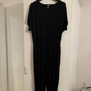 Jumpsuit - Svart jumpsuit. Mudd ner till och resår i midjan. 