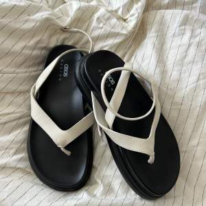 White sandals with thong and black platform. Size 38. Never used because my feet are too narrow. 