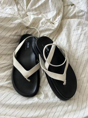 White sandals with thong and black platform. Size 38. Never used because my feet are too narrow. 
