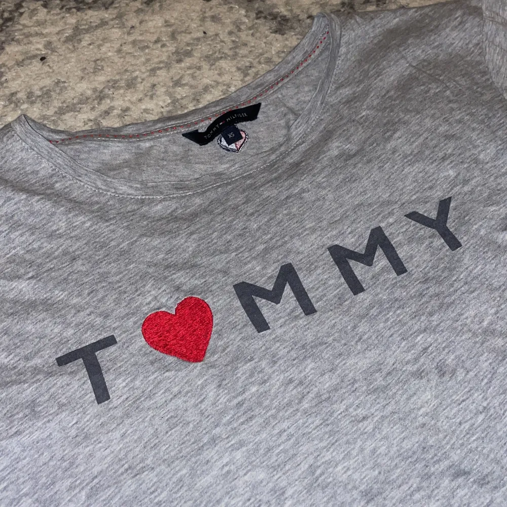 Säljer denna super vibiga Tommy Hilfiger tröjan/ toppen som jag har älskat, använd fåtal gånger. tröjan har även super fina hjärt detaljer, en framför och ett litet bakom nacken som man kan se i bild 3. Nyskick i ljus grå färg. 💕💕. T-shirts.