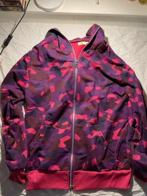 Lila hoodie - Lila hoodie som liknar bape. Priset är diskuterbart. Det är inte de materialet som finns när man köper på amazon. Sitter fint oversized på mig som är XS/S men hoodien är k storlek L.