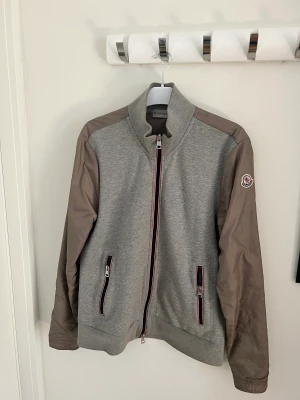Moncler cardigan - Säljer nu min moncler cardigan i bra skick förutom det på högra underarmen och dragkedjan som kan vara jobbig, den är storlek L men passar även M, pris 2499 men priset är förhandlingsbart!  Vh Måns 