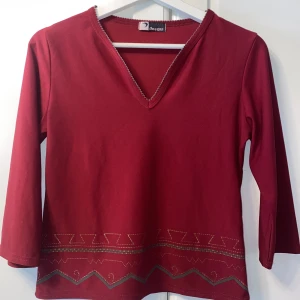 Vinröd topp  - Vinröd topp med 3/4 ärmar. Söta detaljer.  Passar 34/36. 