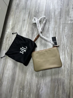 Axelväska - Väska från Ralph Lauren aldrig använd säljer den till 850 kr. Fin och lätt med bra material som alltid från Ralph lauren. 