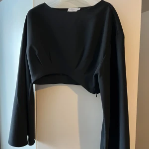 Svart topp - En svart topp från Hanna Schönbergs kollektion tillsammans med NAKD (med vida ärmar) som endast är använd en gång🥹