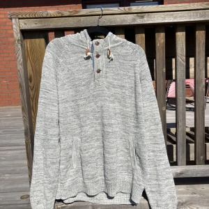 Grå stickad luvtröja - Snygg stickad luvtröja från HM i färgen grå. Går att knäppa med knappar längst upp. Med fickor och luva. 