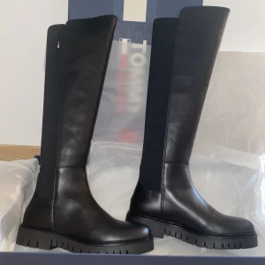 TOMMY HILFIGER stövlar - Jättefina svarta stövlar från Tommy Hilfiger i storlek 36. Stövlarna är köpta över 2000kr men är beställda i fel storlek, de är därmed helt oanvända 