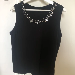 Stickad väst med paljetter - Storlek L men skulle säga att den är aningen mindre. Paljetter vid kragen. Använd cirka fåtal gånger så i fint skick!