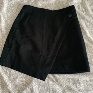 Minikjol monki - Svart minikjol i omlottsmodell från monki! Köpt i höstas, dessvärre blivit förliten. Storlek 34. Jättesnygg med ex en svart croppad kavaj till!