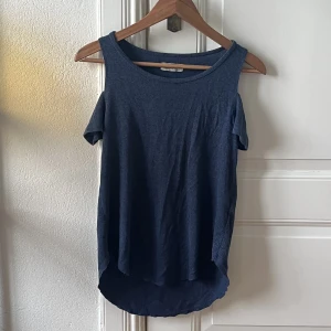 T-shirt  - Mörblå T-shirt från Hollister där axlarna är bara.