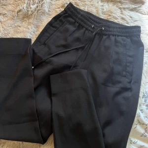 Pull on byxa - Ett par bekväma byxor som är kostymlikande. I strukturvävd kvalite med snören. I en svart färg. Storlek 34. Kan ej visa hur dom ser ut på då dom är små på mig. Använd 2-3 ggr endast.