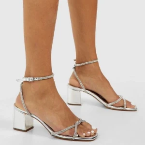 Glitter klackskor - Glittriga klackskor från boohoo med knyten runt foten✨låg silvrig block som är stabil! Glitterstenar på alla remmarna✨ helt nya, dem är inte använda då lappen sitter kvar. Storlek 39