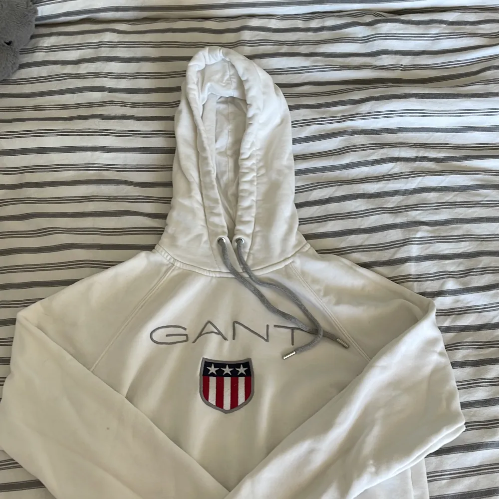 Vit GANT-hoodie i storlek S. Det finns en fläck på slutet av tröjan, har inte testat få bort den men det går säkert bort med fläckborttagning! Den är liten i storleken, skulle säga att den passar en XS. Hoodies.