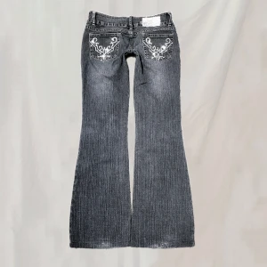 Jeans - Midja: 78 innerben: 77 Jeans med detaljerade bakfickor. Storlek 10, motsvarar ca S. Bootcut. Lite tunnare i materialet. Något använt skick; nötningar enligt ex.bild, majoriteten stenar saknas, nötta fotändar, uppsydda samt lagade på ett ställe.🤍