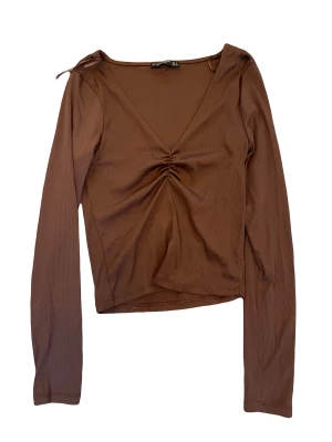 Brun topp - Brun v-neck topp som jag köpte i stradivarius när jag var i Spanien men aldrig använt, kunde inte hitta modell bilden på hemsidan så tror inte att dem säljer den fortfarande köpt för 220