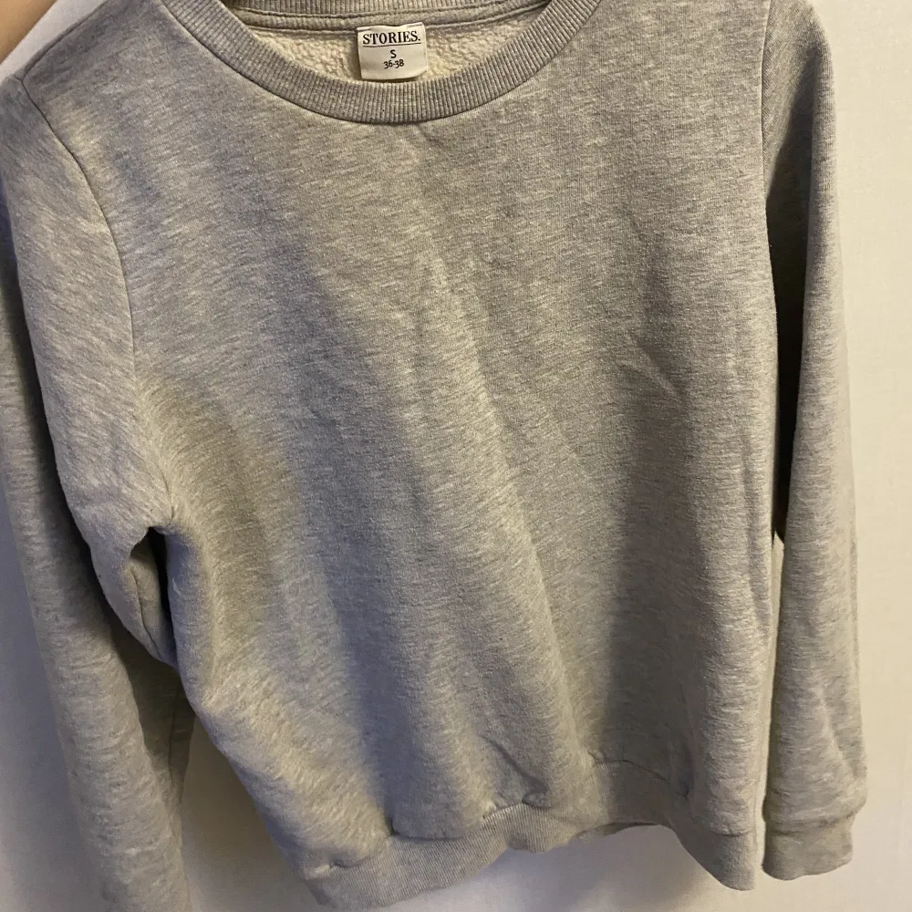 Grå sweatshirt från märket stories. Tvättat några gånger, är i okej skick.. Tröjor & Koftor.