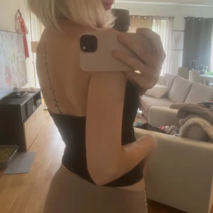 Topp - Svart topp med öppen rygg och knytning runt halsen i superskönt material. Storlek xs/s! Sparsamt använd💕