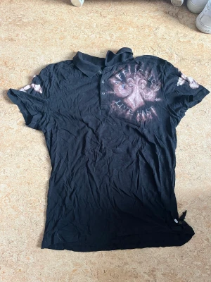 Affliction thin polo - En tvär fet affliction polo i tunn material, finns ett stort jävla hål i tröjan vid sidan i ungefär vid kanten av tröjan men det gör ba att tröjan ser fetare ut.