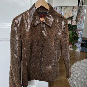 Skinnjacka brun, krokodilmönster  - Faux hela vägen!  Fin jacka köpt i år, aldrig använd pga lite för liten.   Jättefin färg och i bra skick!
