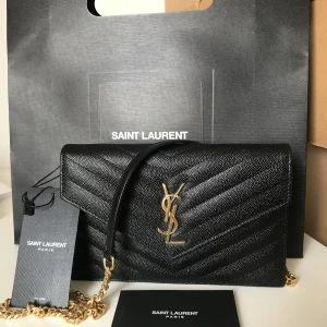 YSL WOC väska - Yves Saint Laurent wallet on chain i mycket fint skick. Använd endast ett fåtal gånger med etiketten fortfarande kvar på. Väskan kan användas som axelväska, crossbody samt clutch. Innehåller en ficka samt 6 korthållare. 