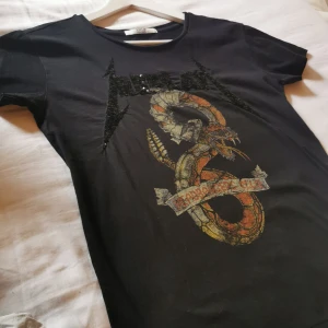 Svart t-shirt - Cool t-shirt med många detaljer. Riktigt rockig! Står ingen storlek men sitter som en S/M. Vill man ha den oversized passar den även XS. Inget tryck på ryggen. 