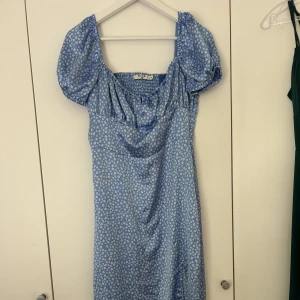 Blå klänning - En super fin blå klänning, med blommor på! Använd en gång, i nyskick! Köparen står för frakten!