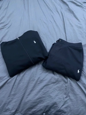 Svart polo Ralph lauren tracksuit  - Svart polo Ralph lauren tracksuit i bra skick tröjan är använd ca 5 gånger och byxorna använda lite mer men i bra skick , båda är i L men passar M, nypris ca 3000 kr