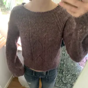 Lila stickad tröja som är lite off-shoulder