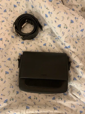 Svart väska  - Slutsåld. Extremt rymlig väska från Carin Wester. Man får plats med allt och lite till trotts att den är så liten. Svart band och band från Carin Wester följer med. Nyskick 