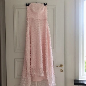 Ida Sjöstedt blommig klänning stl 36 - Rosa axelbandslös Ida sjöstedt-klänning med blomapplikationer. Stl 36. Midi längd och lite kortare framtill. Mycket fint skick! 